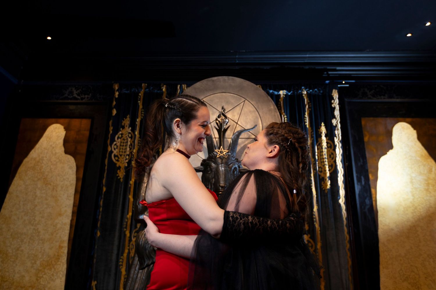 Two people in formal attire dance together in an elegant ballroom setting with dramatic lighting.