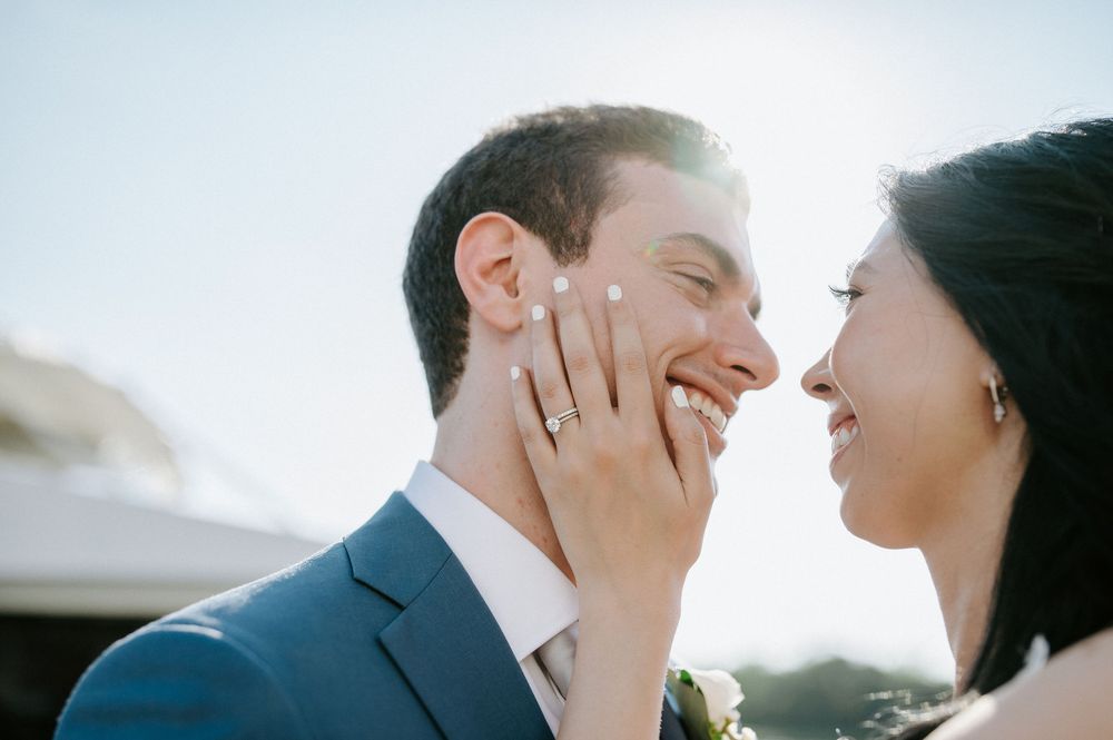 A tender close-up moment between a couple against a bright, ethereal background.
