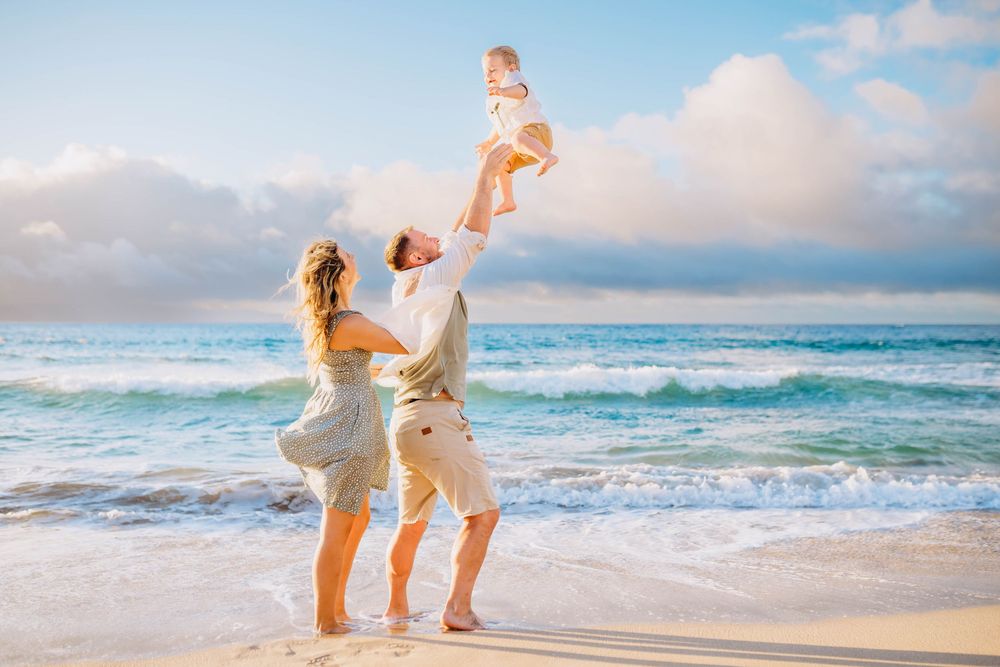 Happy couple walking and playing together on a tropical beach at sunset with ocean waves in the background.