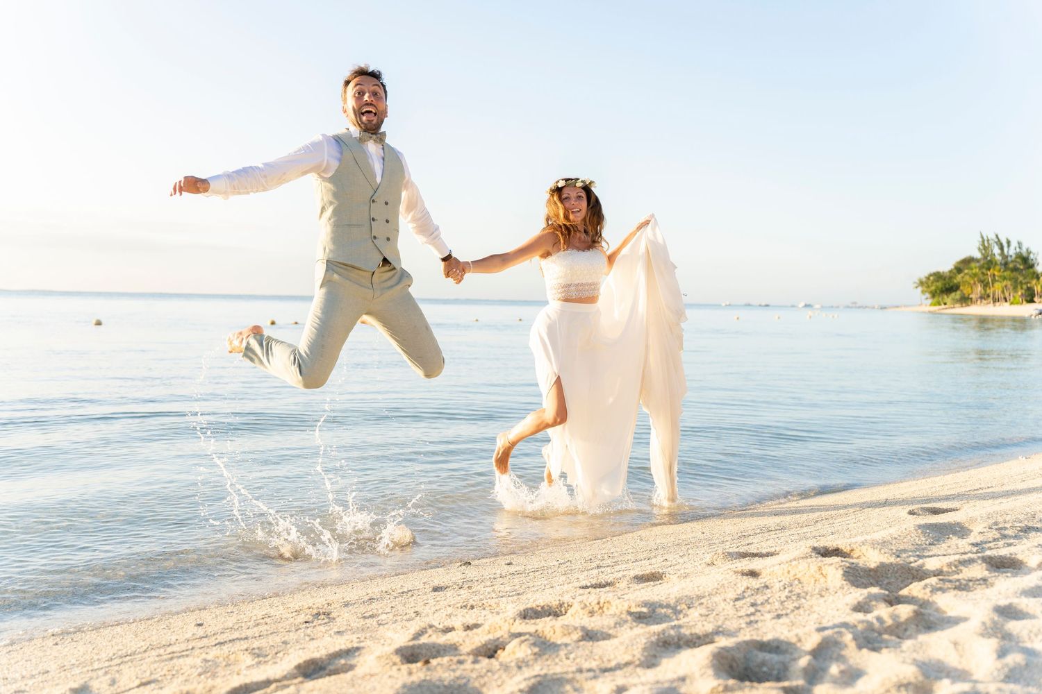Couple walking and splashing along a sandy beach at sunset.
