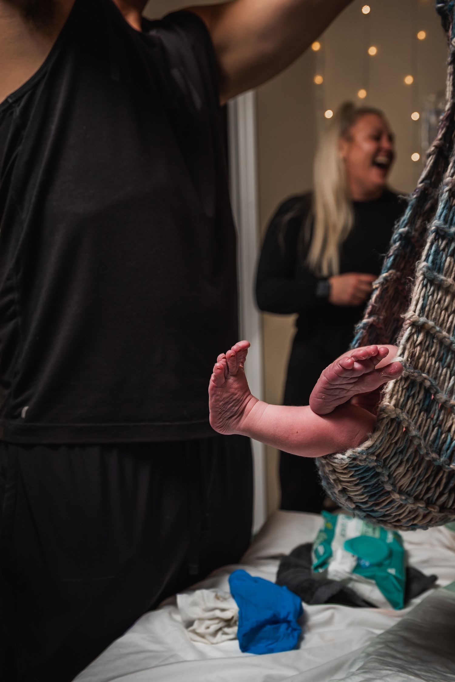 A photo of a newborn baby being weighed in a birth sling moments after delivery at home.