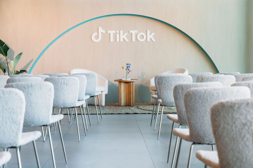Elegant restaurant interior with light blue walls and white chairs arranged in rows along modern dining tables.