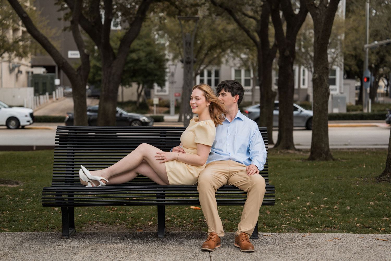 A romantic couple shares tender moments under an arched colonnade against a textured concrete wall.