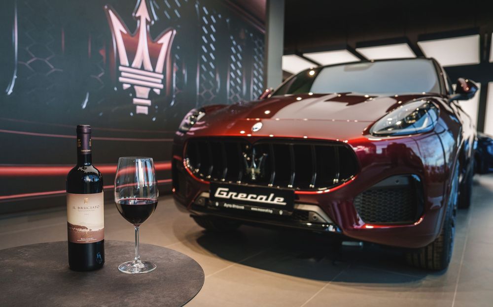 A sleek black luxury sports car displayed in a dimly lit showroom with red accent lighting.