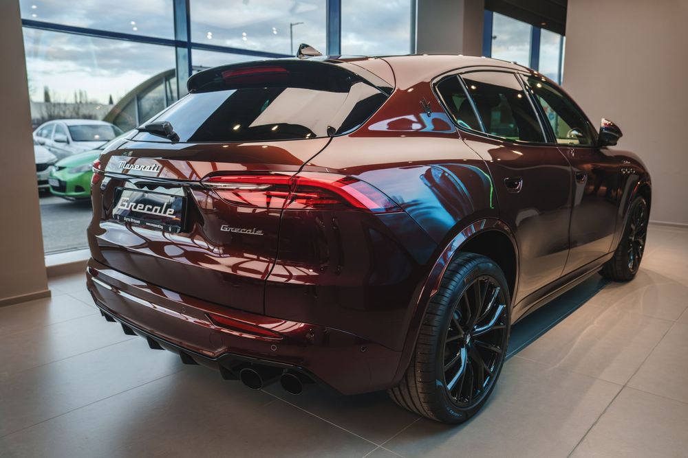 Black BMW M5 CS sports car shown from multiple angles in a modern car dealership showroom.