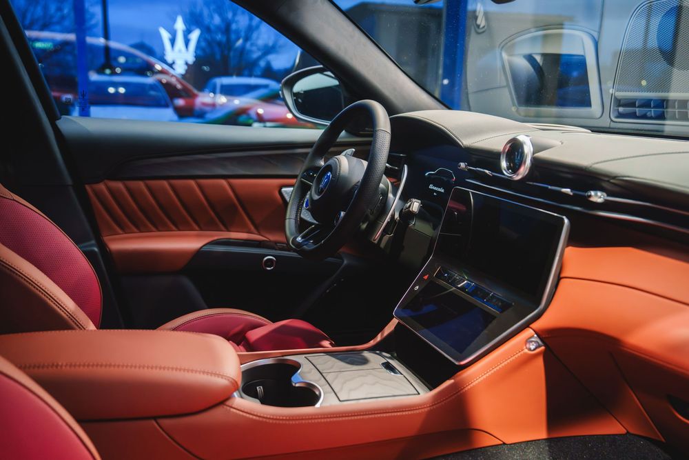 Luxury car interior featuring orange leather seats and modern dashboard with large touchscreen display at night.