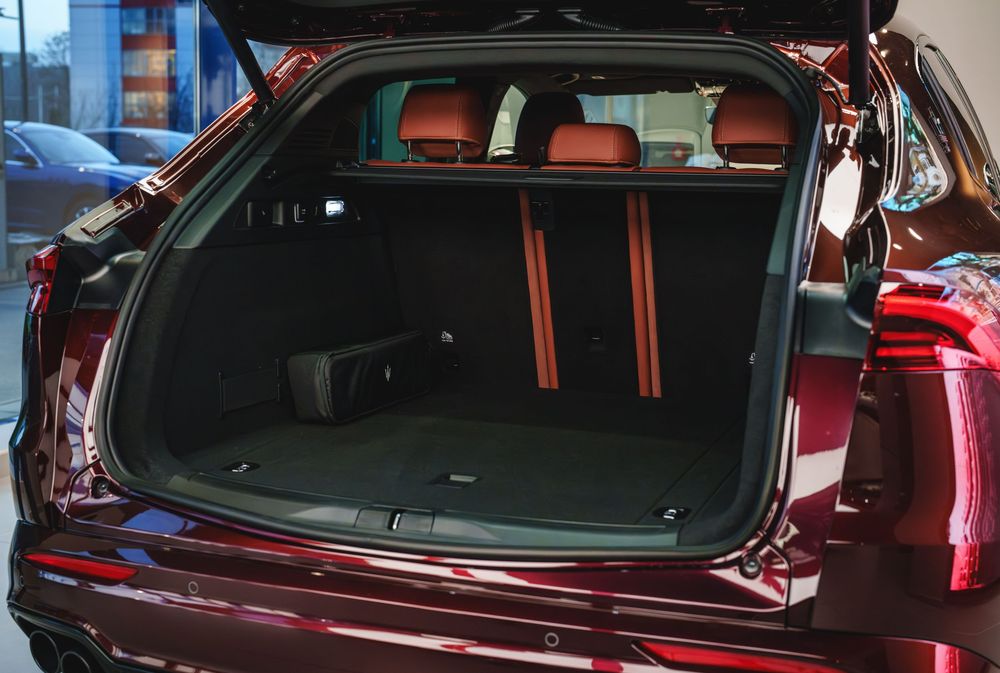 Spacious cargo area of a luxury SUV with burgundy exterior and red-trimmed black leather interior.