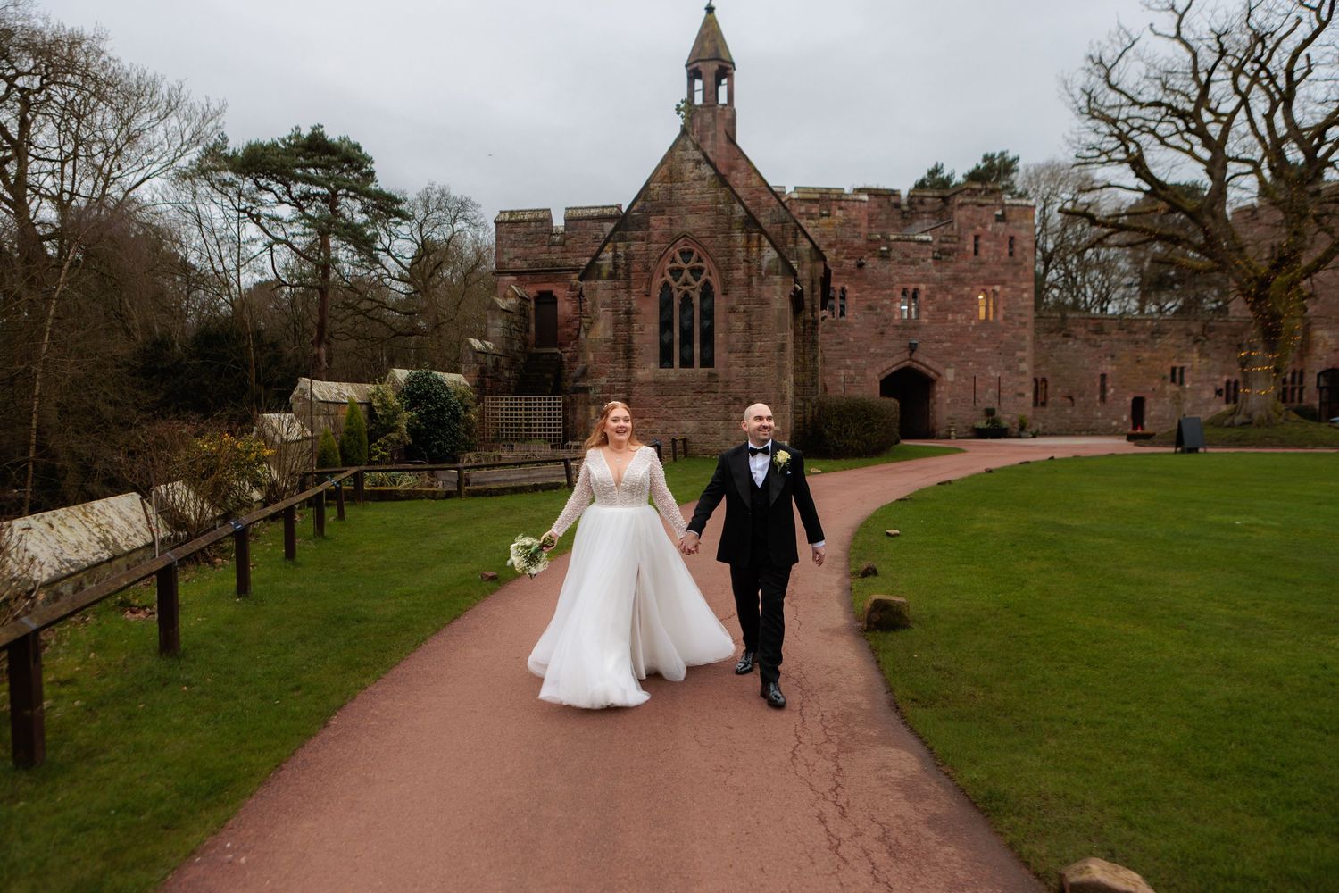 Large group photo of wedding guests gathered outside a historic stone church with Gothic architecture.