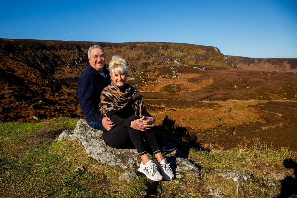 couple photography on boulder in wicklow countryside overlooking dramatic mountain scenery.