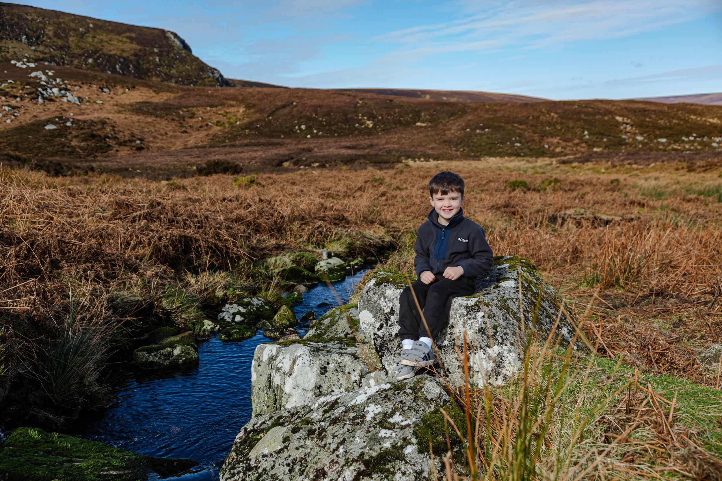 Boy photographed in scenic peatland landscape with rocks and streams