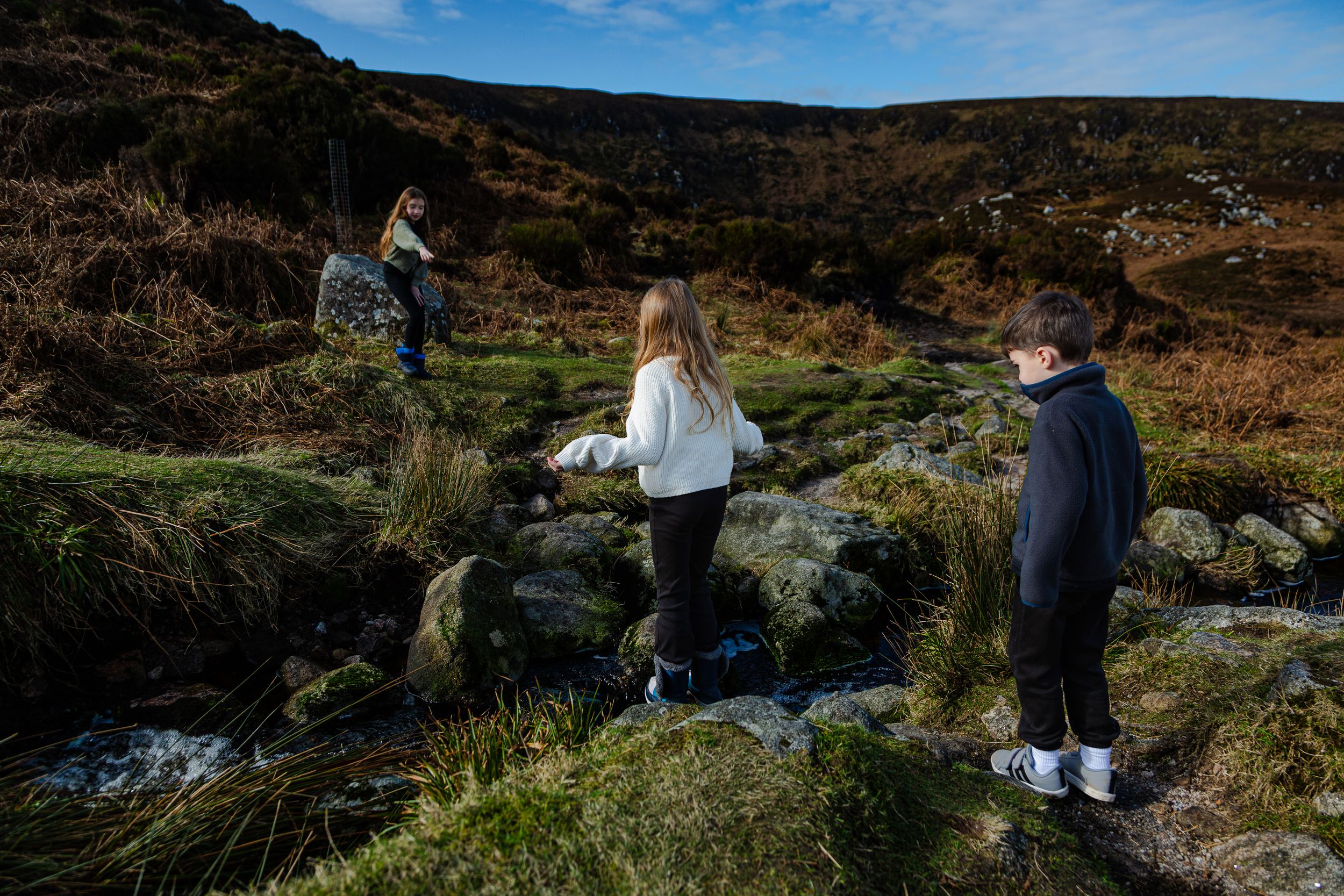 vacation photography of children enjoying the nature in wicklow while crossing the streams.