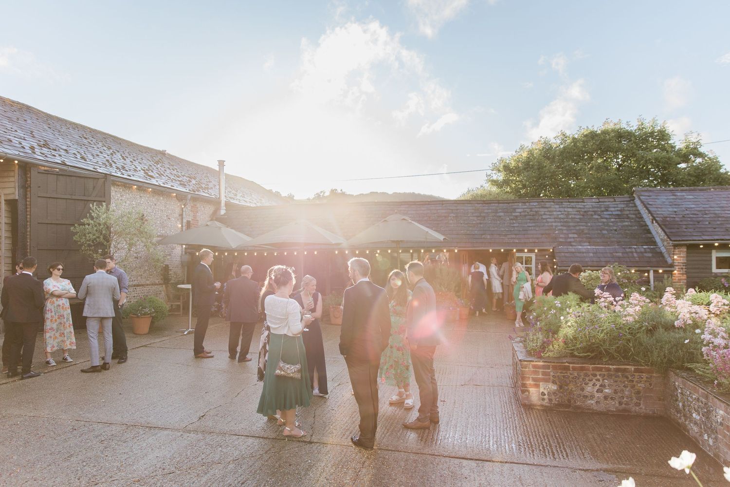 A sequence of outdoor wedding ceremony photos showing guests mingling at sunset with a rustic barn backdrop.
