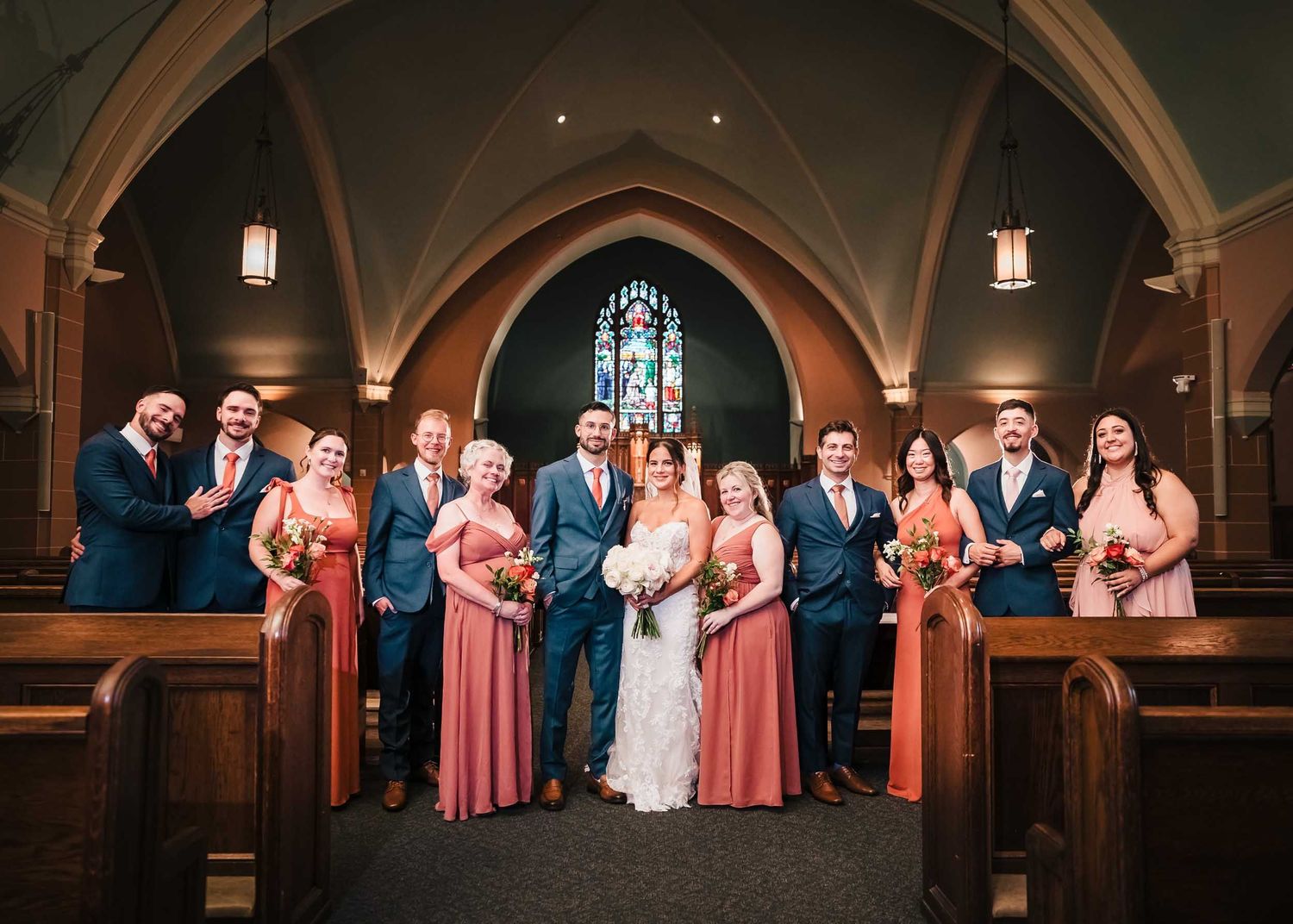 Bride and groom with their wedding party posing inside Saint Brigid Church in South Boston