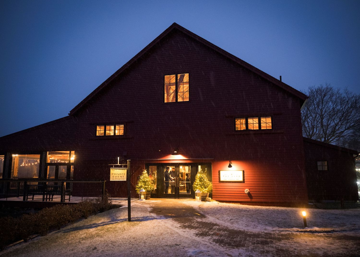 Rustic barn wedding reception venue with wooden beams, chandeliers and round tables set for an elegant celebration.