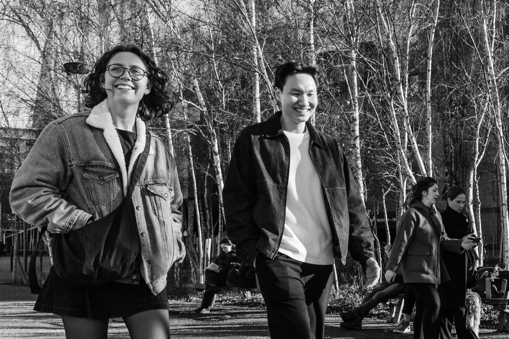 Two people walk together outdoors in a black and white photo with bare trees visible in the background.