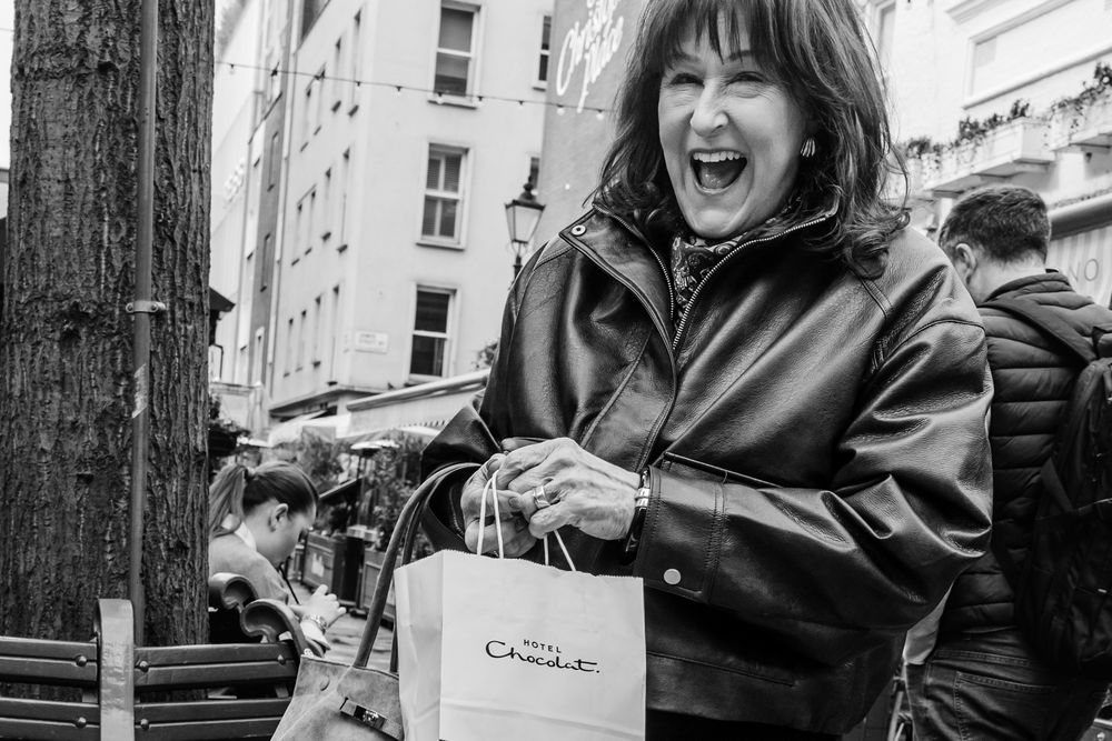 A series of five black and white photos showing someone in a leather jacket posing expressively on a park bench.