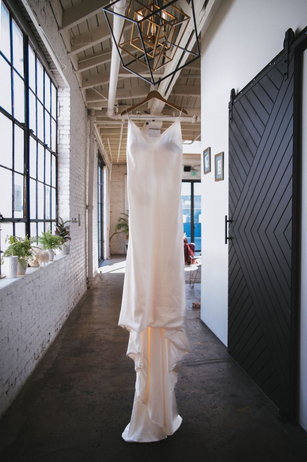 A series of four connected photos showing a ghostly white figure walking through a stark industrial hallway with white columns.