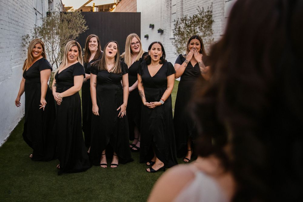 A group of people wearing black dresses sit together outdoors for a formal photo session.