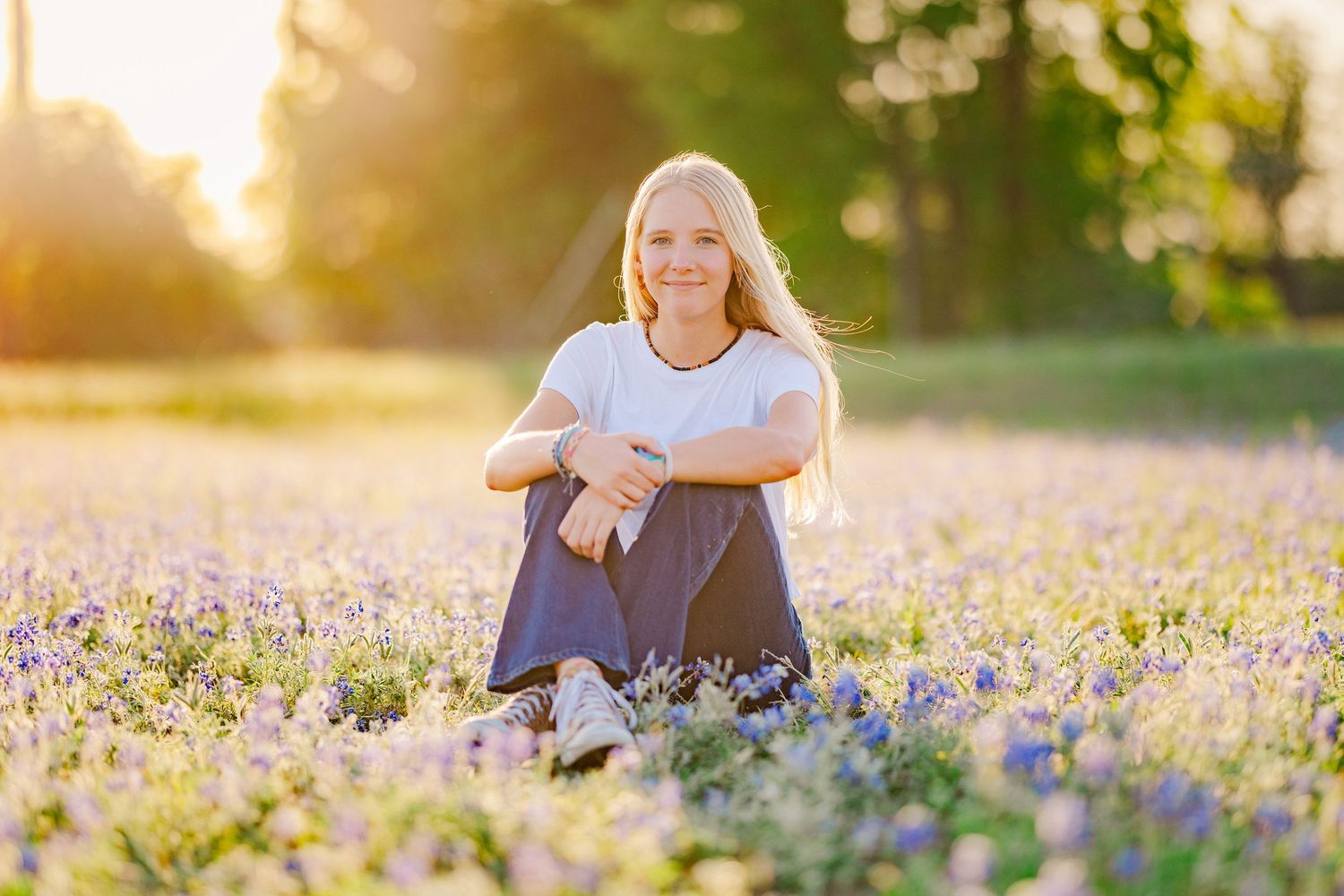 Young woman sitting in blooming bluebonnets during a Central Texas spring mini session with natural light photography.