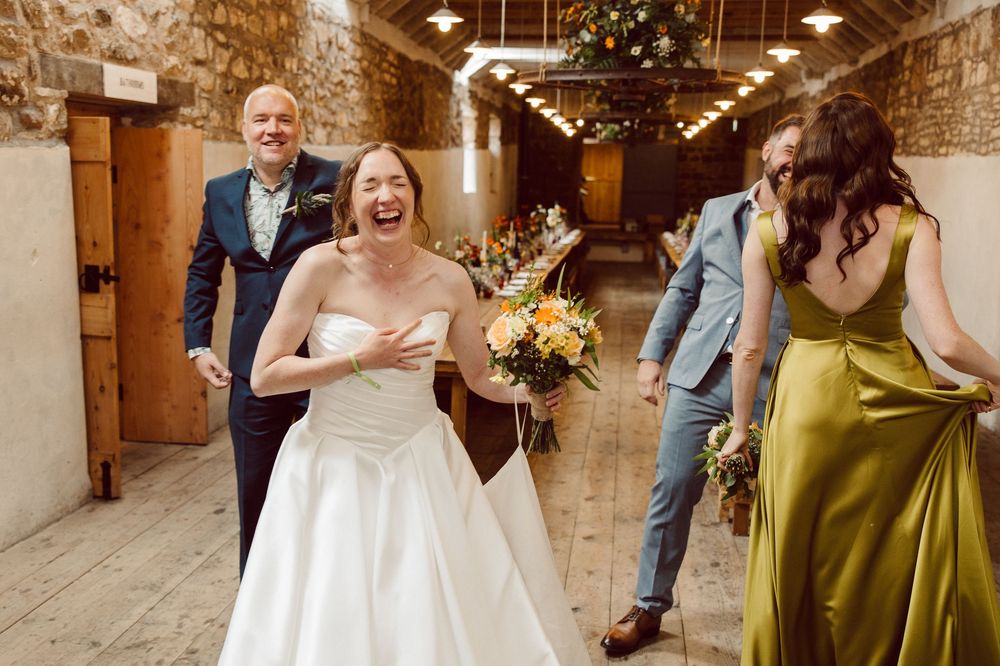 A candid moment of joy and laughter in a rustic stone hallway during a wedding celebration.