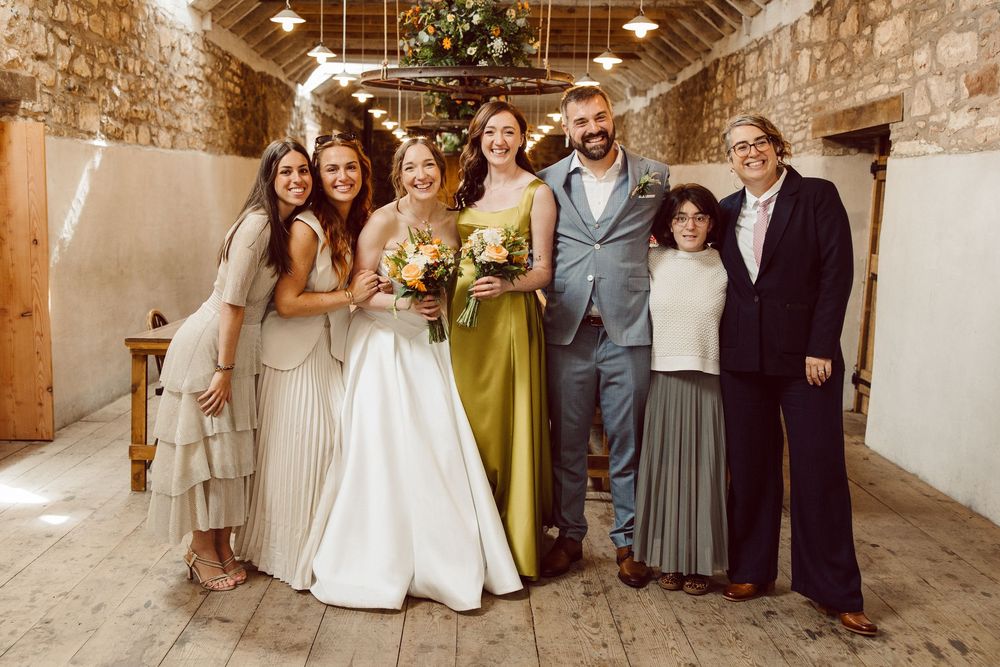 Wedding party poses together in rustic stone venue during celebration.