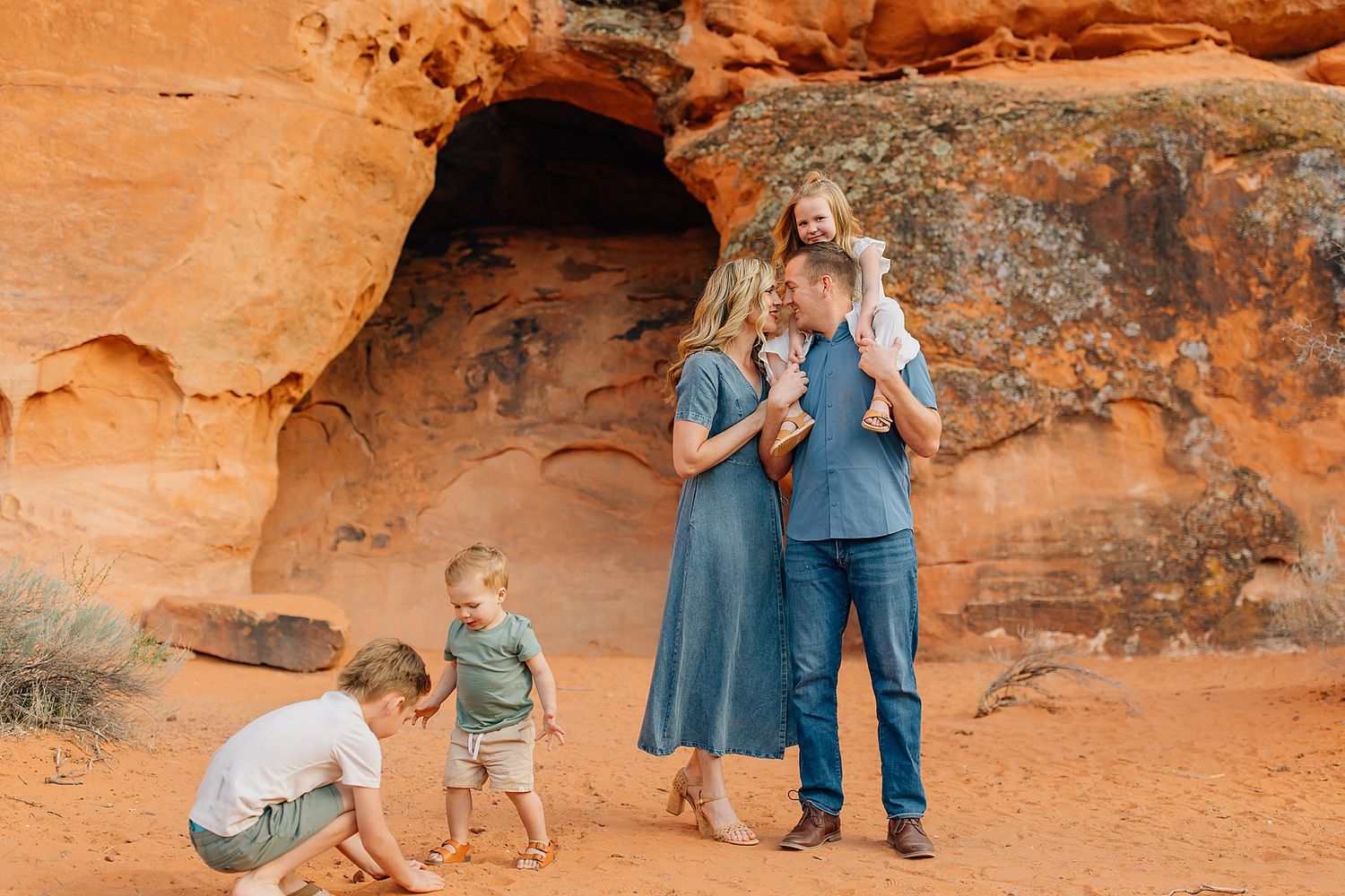A group stands together against red rock formations in a desert landscape during golden hour.
