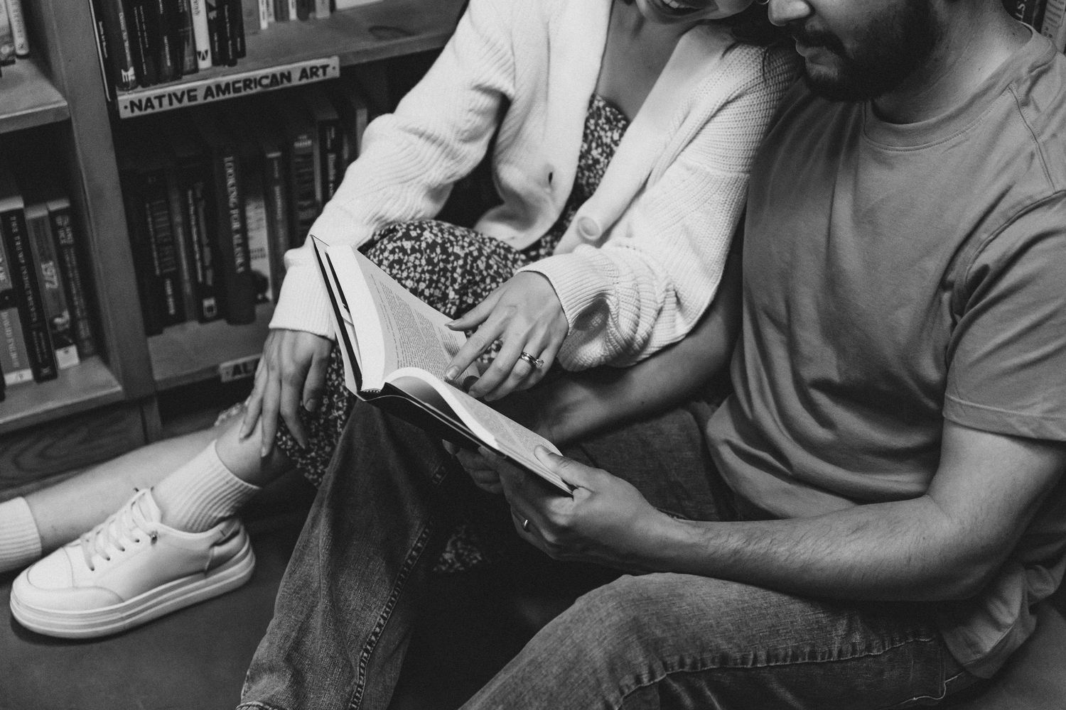 Black and white image shows couple sitting in a North Carolina book store reading a book together .