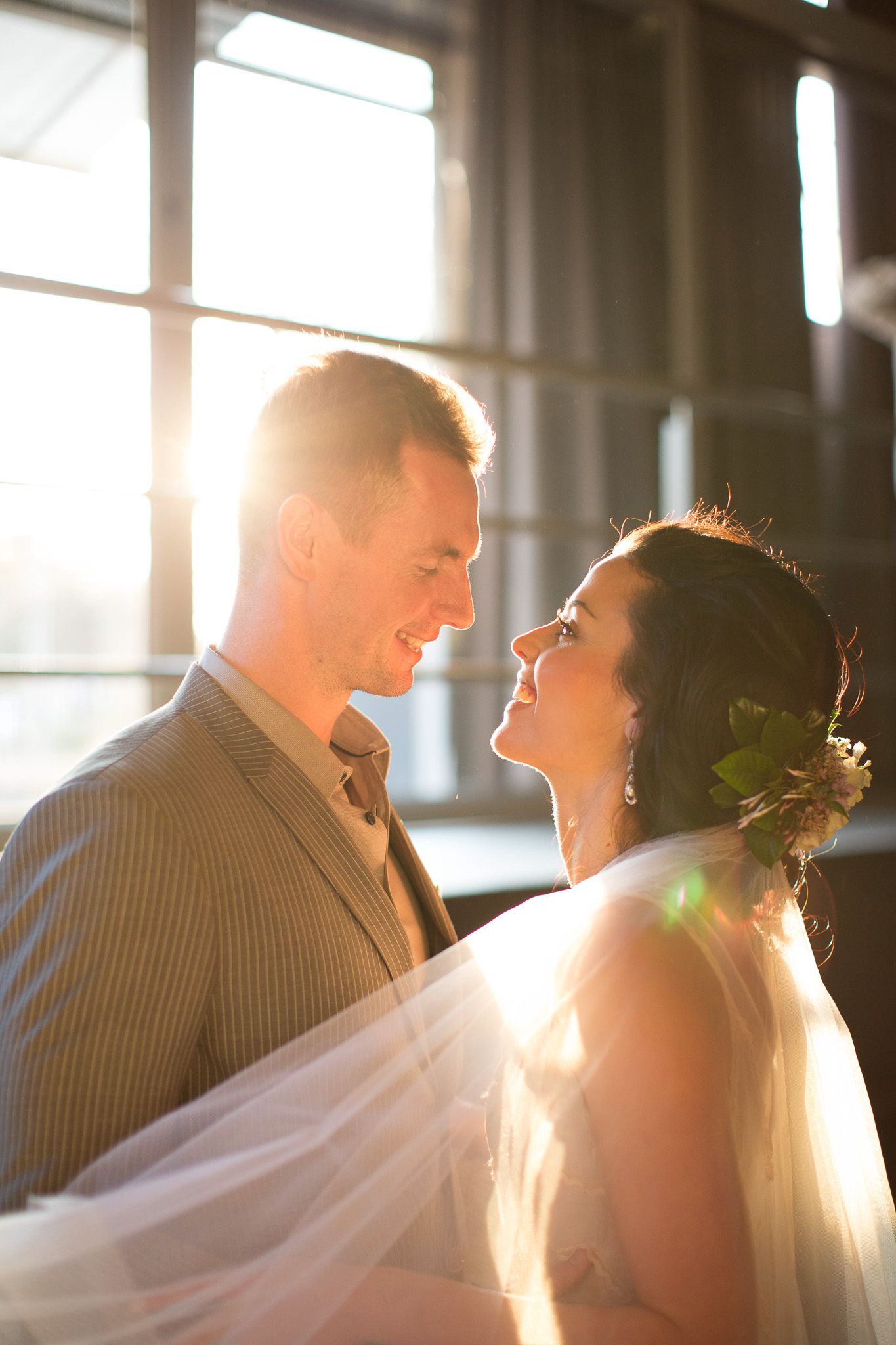 Bride and groom laughing together with stunning golden sunlight behind them.
