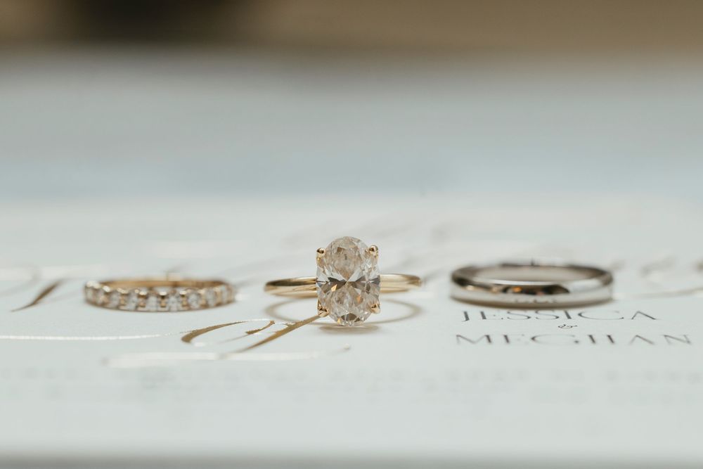 A collection of delicate gold wedding rings and engagement rings arranged in a row on a light surface.