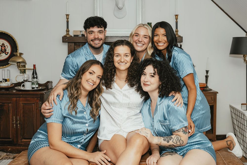 A group wearing coordinated blue and white outfits poses together on a couch for a casual indoor photo session.