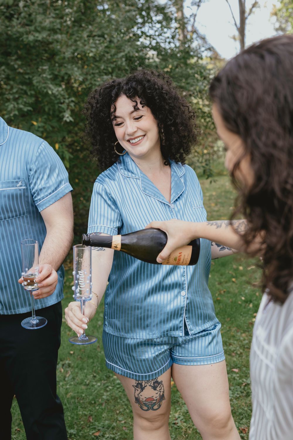 People enjoying drinks outdoors while wearing casual summer attire in a garden setting.