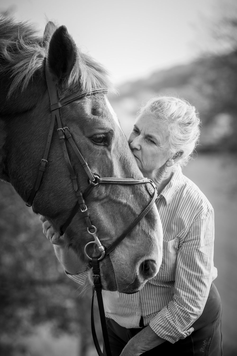 A series of black and white photos showing tender moments between a person in white and a horse nuzzling together.