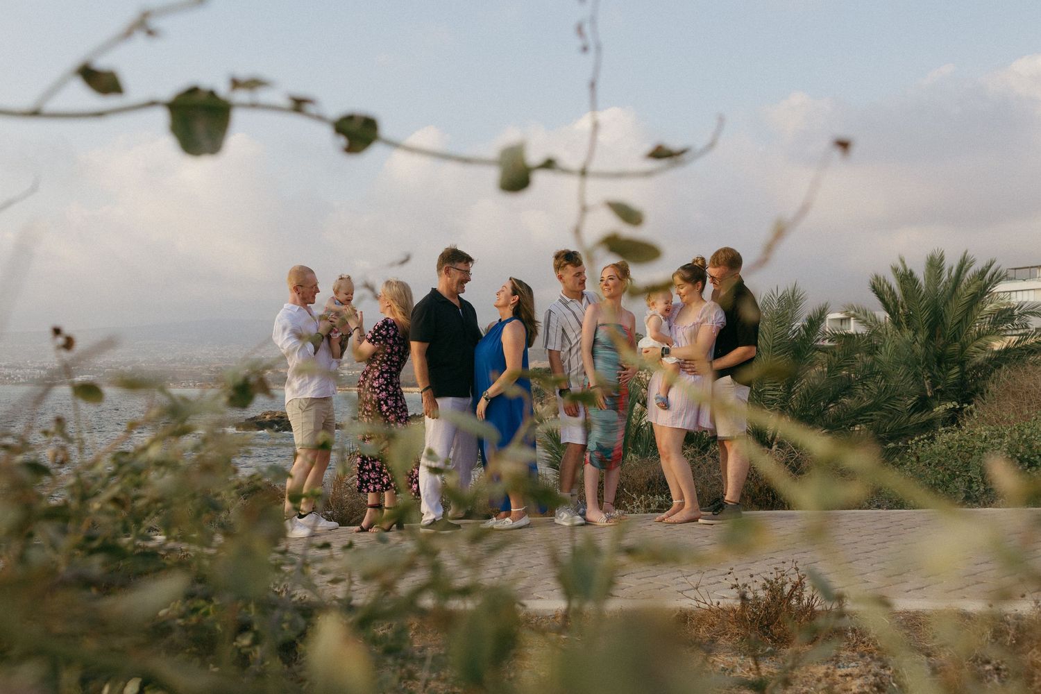 A family walking along a scenic coastal path during sunset family photoshoot with palm trees in the background.