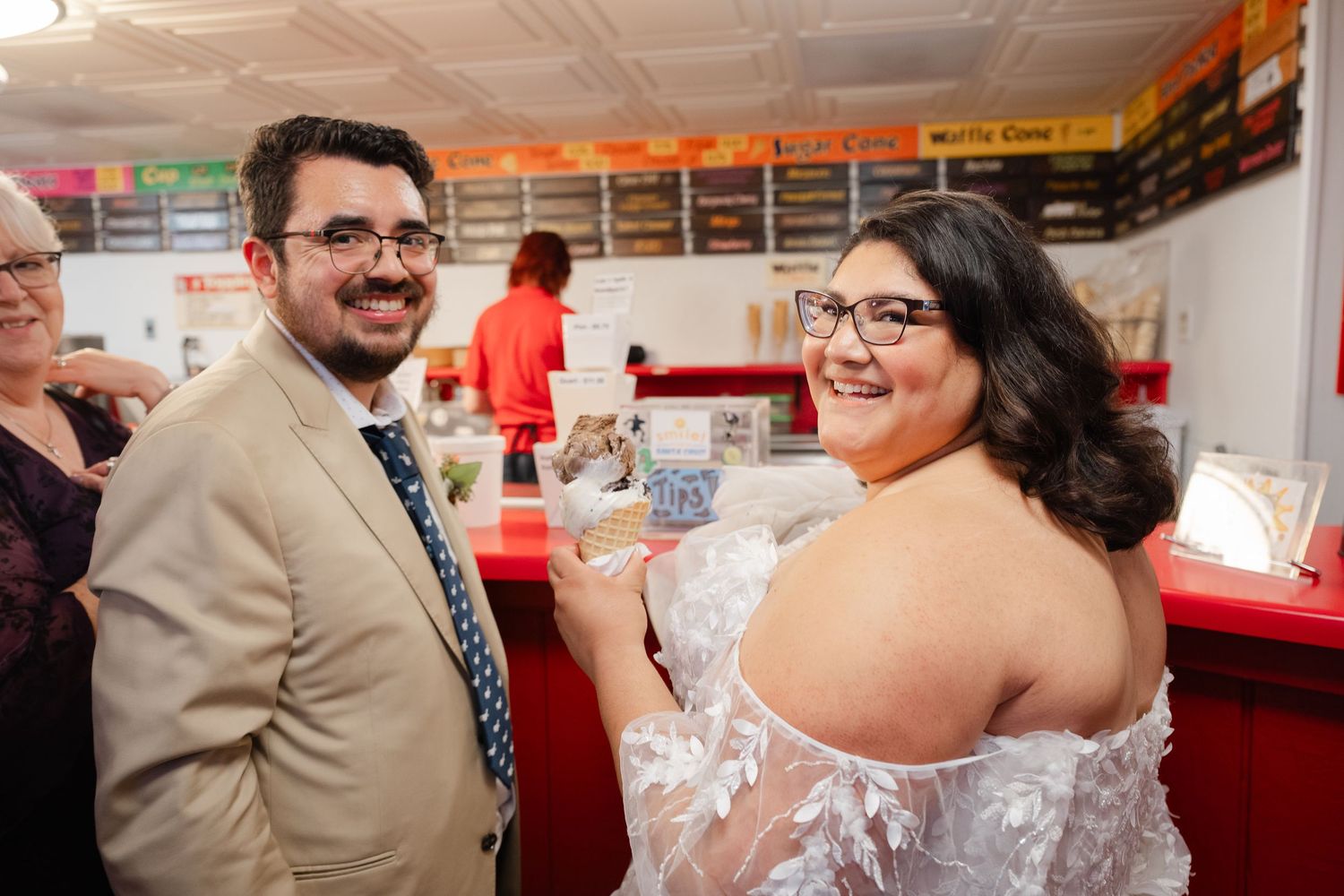 Two people share a joyful moment while celebrating at an indoor event with orange decorations overhead.