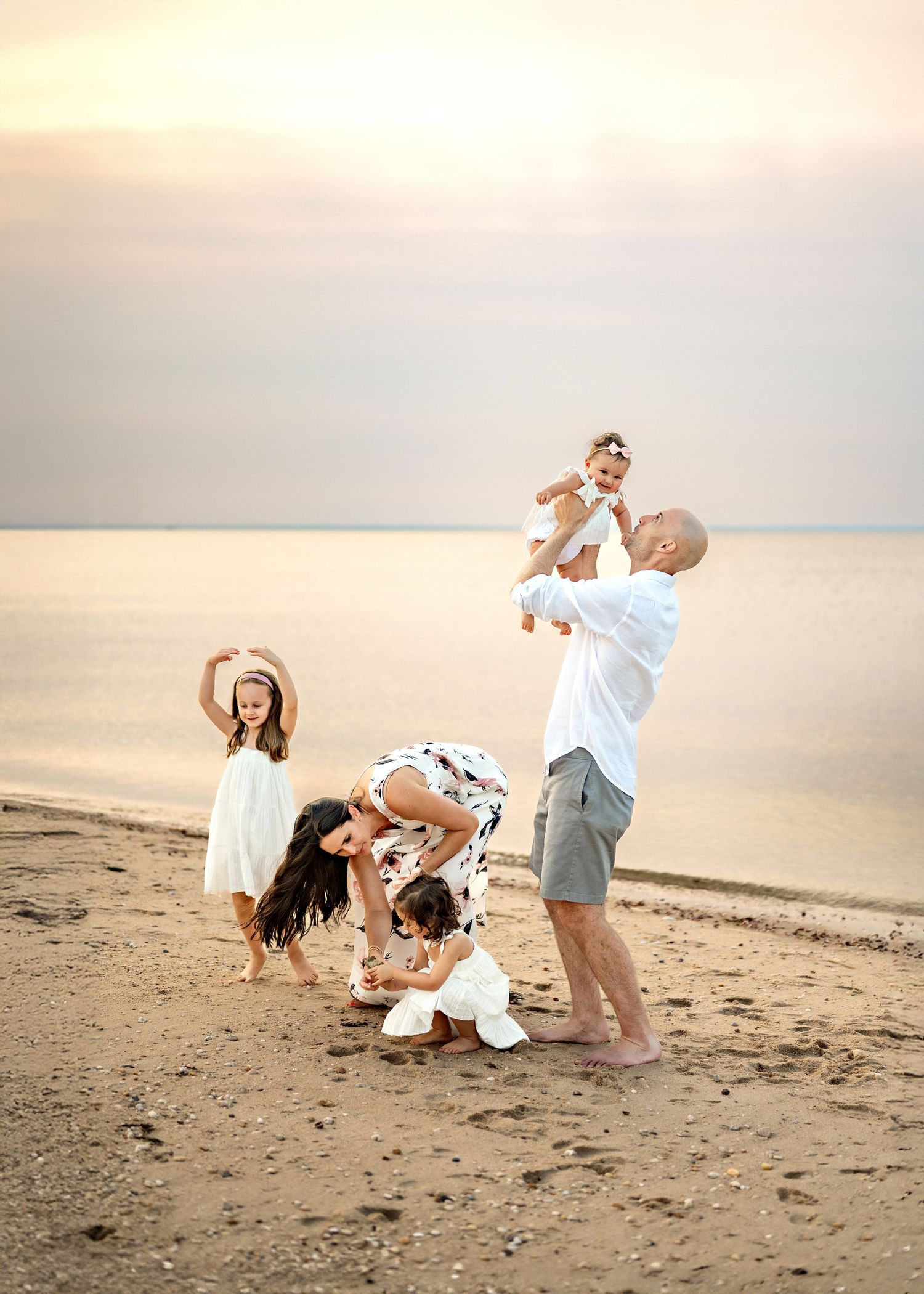 A family playfully runs and chases each other along a peaceful beach at sunset creating joyful moments together.