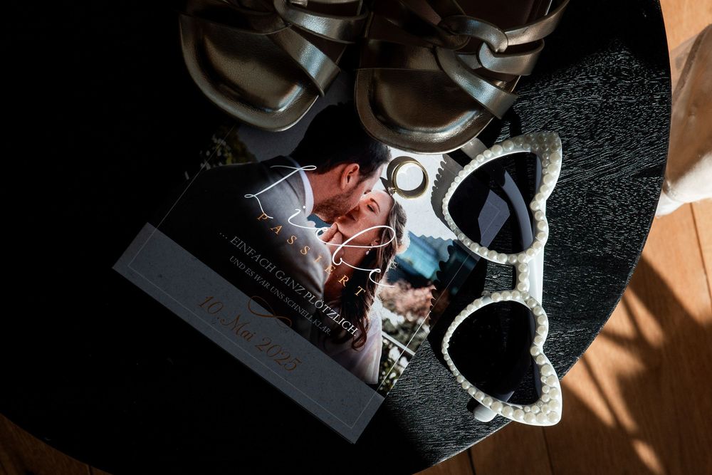 Hochzeitsdetails: Brautschuhe und herzförmige Sonnenbrille stilvoll arrangiert. Kreative Detailfotografie am Niederrhein.