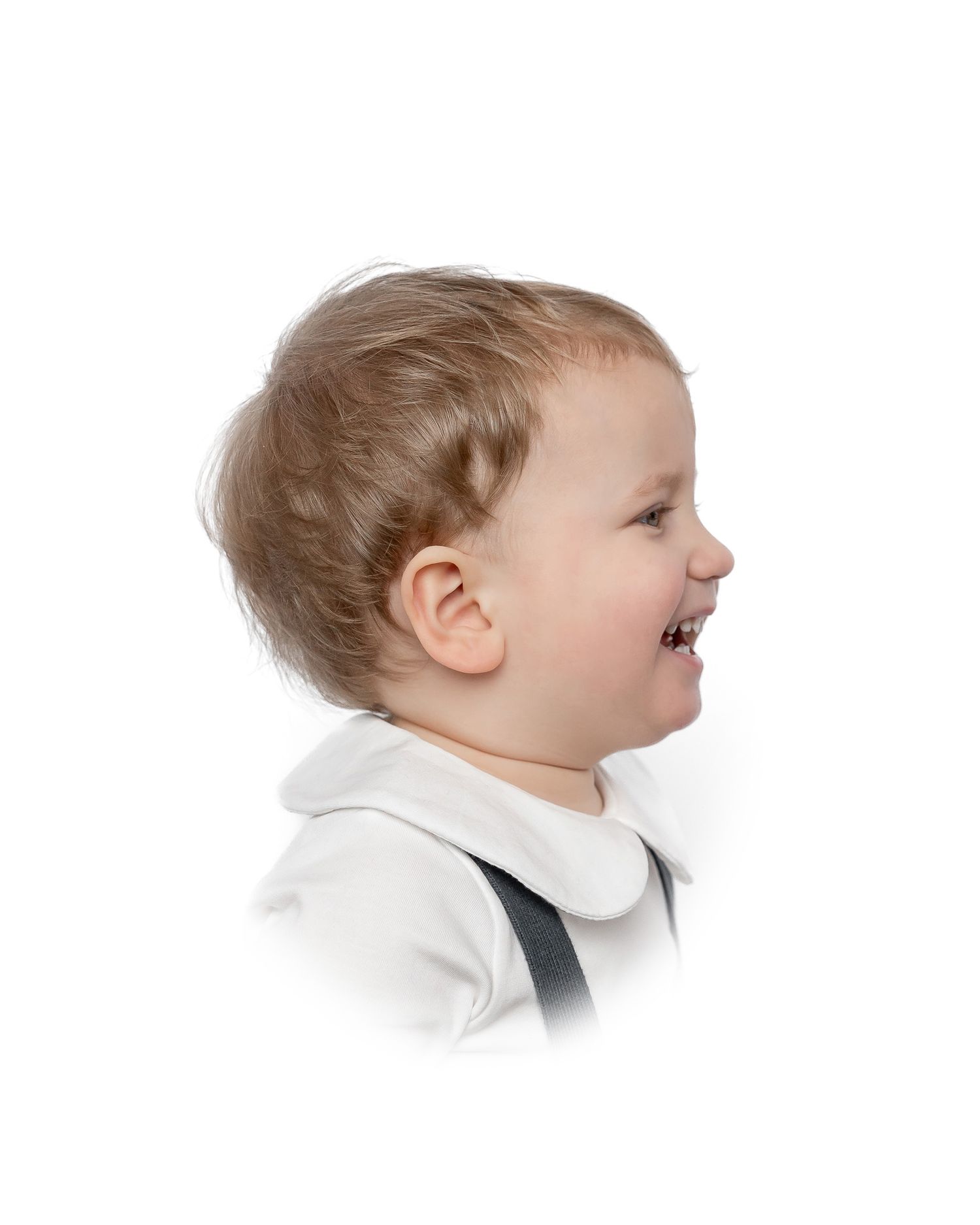 A happy child with blonde hair wearing a white lace dress smiles brightly against a white background.