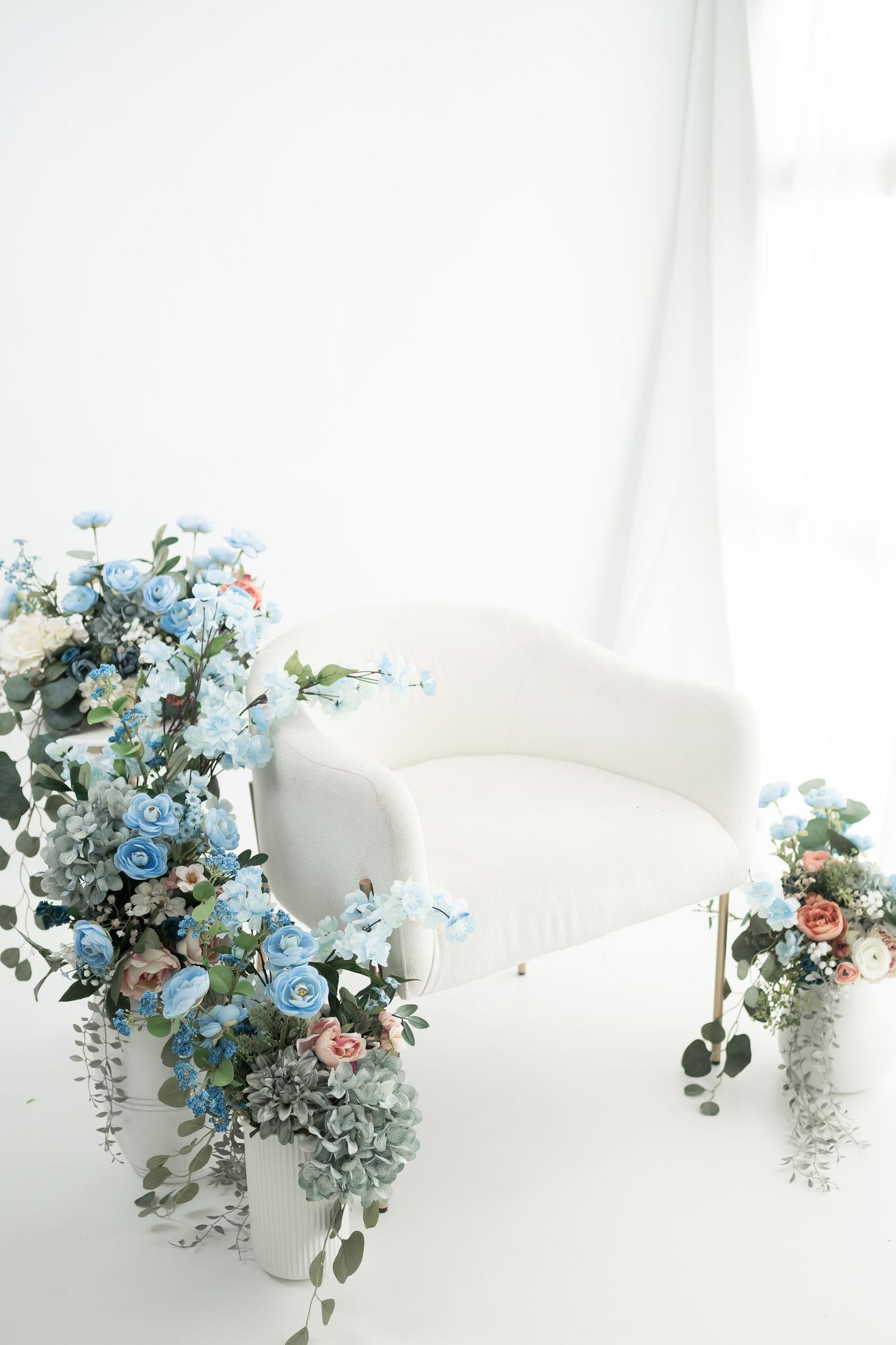 Series of soft blue and pink floral arrangements with eucalyptus displayed on white surfaces in a bright setting.