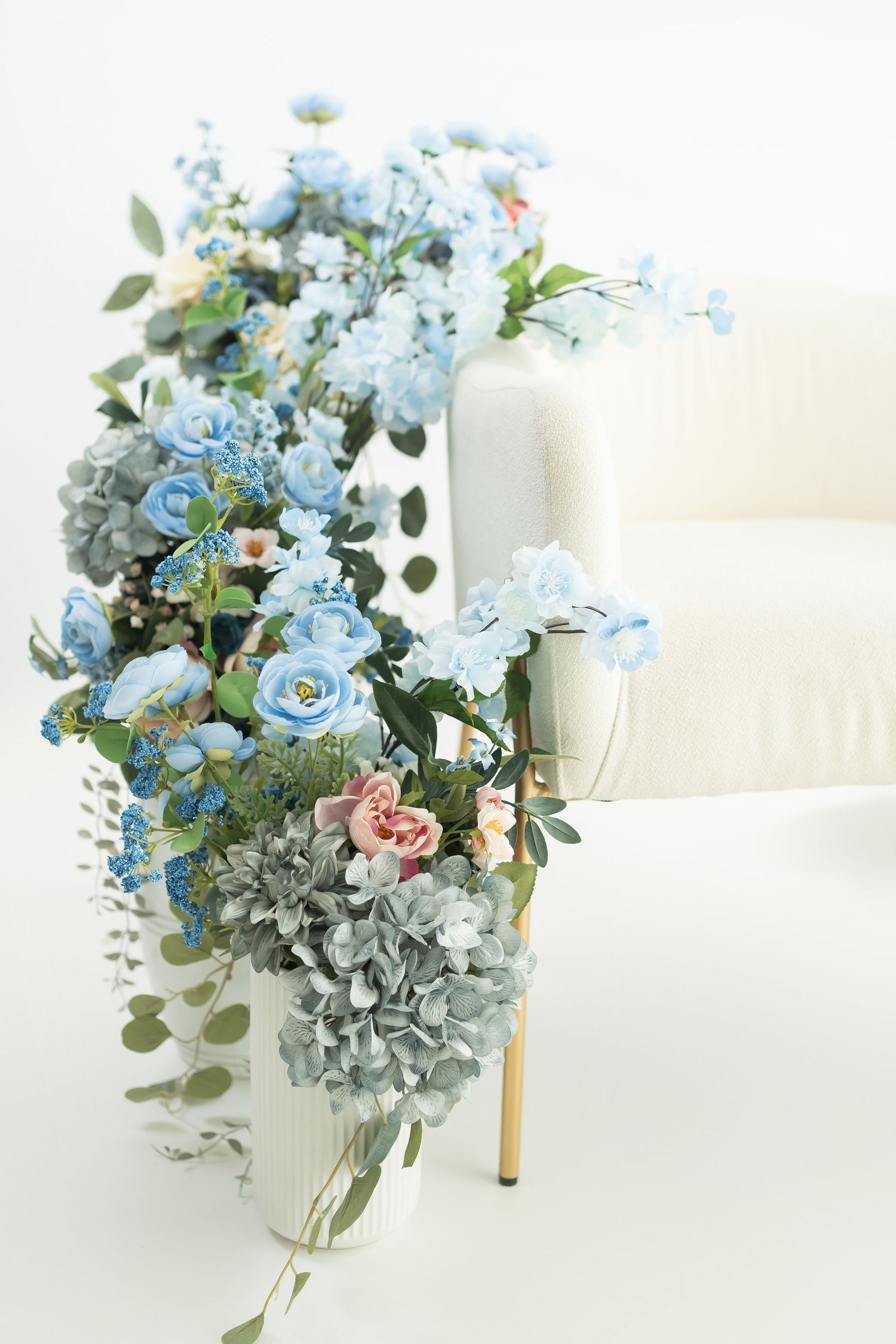 Delicate blue and pink floral arrangement with eucalyptus in white vase creates soft romantic centerpiece.