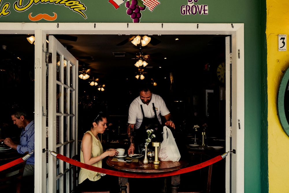 Interior of a restaurant showing dining tables, pendant lights and customers being served.