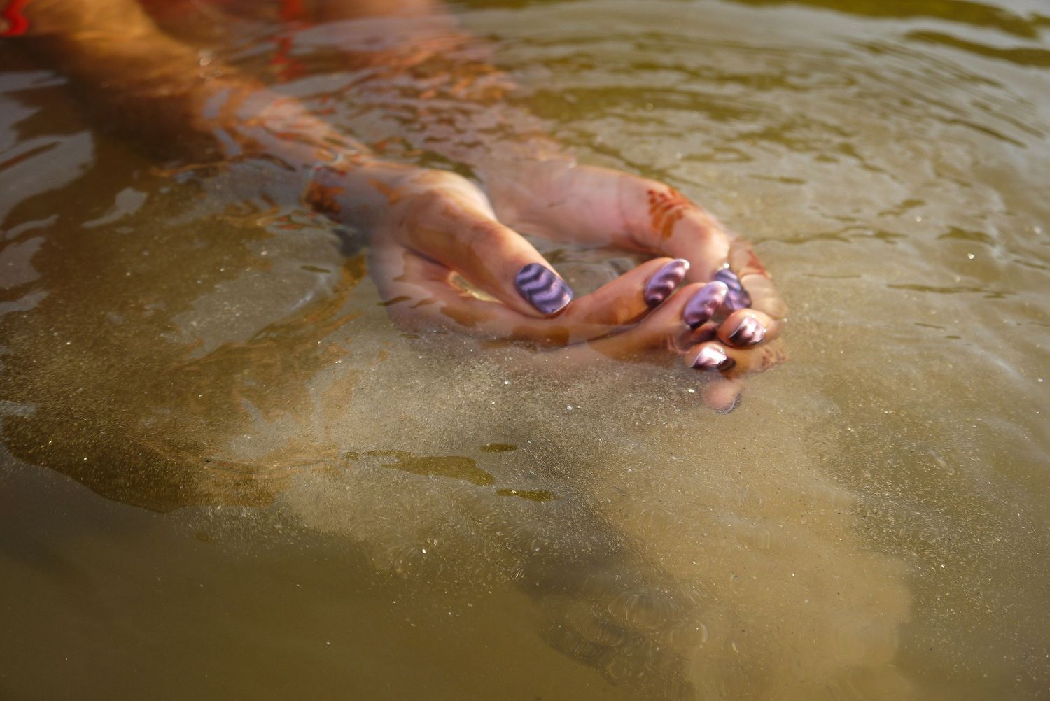 close-up photograph of a girl's hands cupping silt and creek water