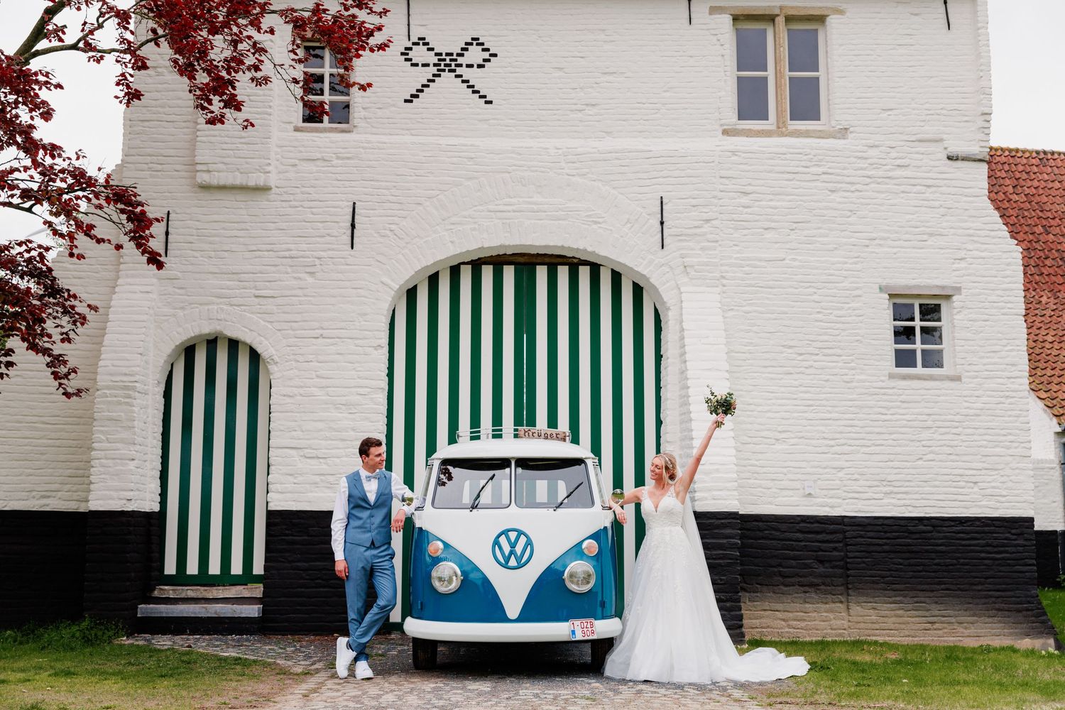 Classic VW bus in blue and white parked outside a white building with green striped awnings.