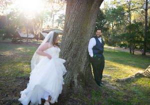 Romantic wedding photo shoot under large oak trees during golden hour.