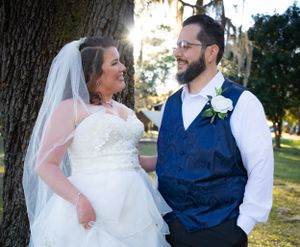 Wedding couple shares joyful moment together under trees in outdoor setting.