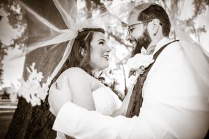 Black and white wedding portrait capturing genuine laughter and emotion outdoors.