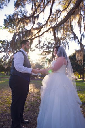 A romantic wedding photoshoot under Spanish moss draped trees during golden hour at sunset.