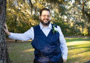 A wedding couple posing in front of Spanish moss hanging from trees in a natural outdoor setting.