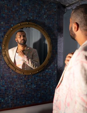 Round mirror on blue mosaic tile wall reflects preparation moments.