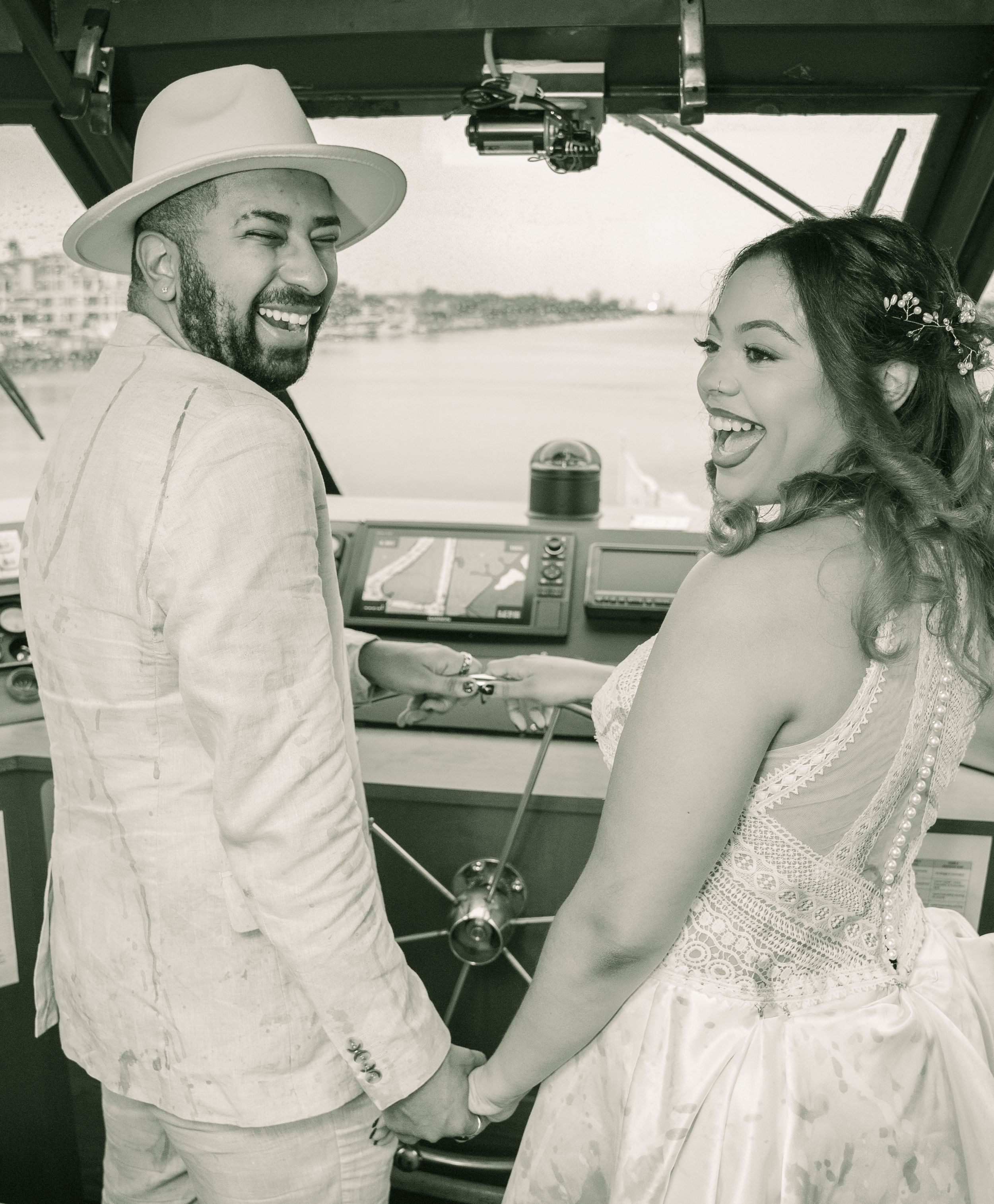Black and white photograph showing a couple sharing a joyful moment in a vintage car.