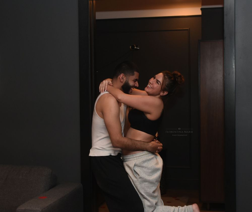 A joyful moment between two people embracing and laughing in a dark hallway.